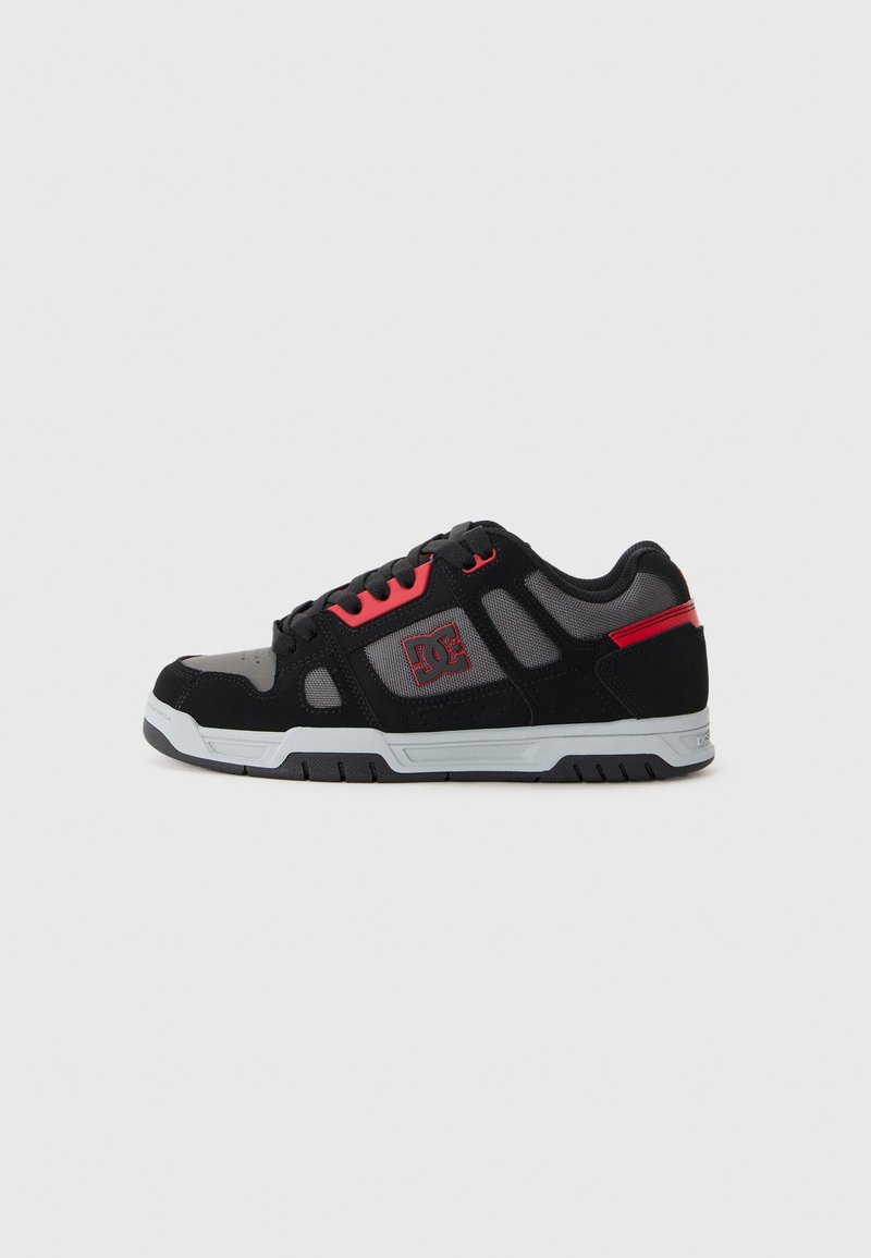 Black and gray athletic shoe with mesh and suede upper, red accents, rubber sole, and prominent logo on the side. Low-top design.