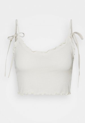 Lichtbeige cropped top met geribbelde textuur, geplooide zoom en halslijn, verstelbare strikbandjes. Eenvoudig ontwerp, geschikt voor casual gebruik.