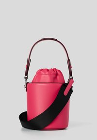 Borsa a secchiello rosa brillante con chiusura a coulisse, manico superiore e ampia tracolla nera regolabile su uno sfondo semplice.
