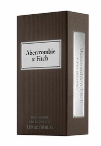 Brun ribbad låda med en silveraccent och etikett i vitt. Texten lyder "Abercrombie & Fitch First Instinct" och inkluderar produktinformation längst ner.