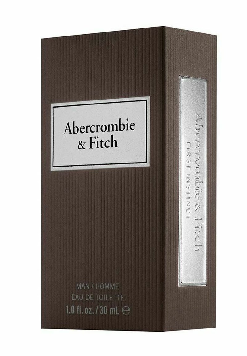 Brun ribbad låda med en silveraccent och etikett i vitt. Texten lyder "Abercrombie & Fitch First Instinct" och inkluderar produktinformation längst ner.