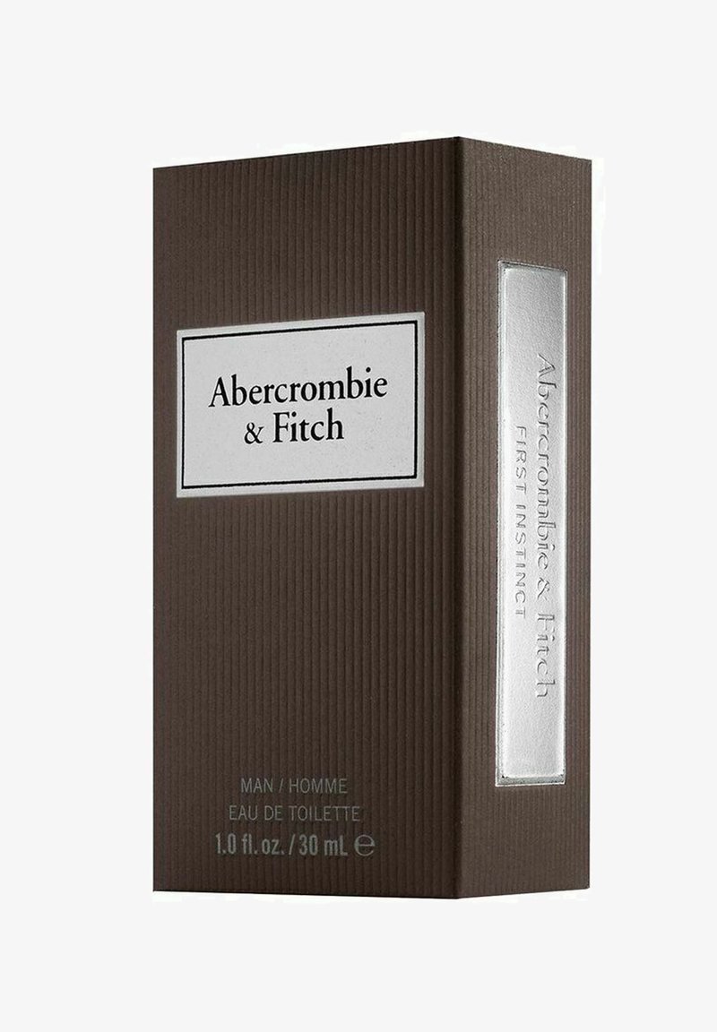 Brun ribbet kasse med sølvaccent og hvid etikette. Teksten lyder "Abercrombie & Fitch First Instinct" og inkluderer produktdetaljer nederst.