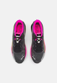 Scarpe da corsa nere con accenti rosa, materiale in rete e superficie testurizzata. Presentano una striscia gialla a contrasto e un sistema di allacciatura.