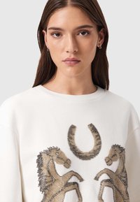 Λευκό φούτερ με περίτεχνη κεντητική διακόσμηση δύο αλόγων και σχέδιο πετάλου. Μαλακό ύφασμα με άνετη εφαρμογή και στρογγυλή λαιμόκοψη.