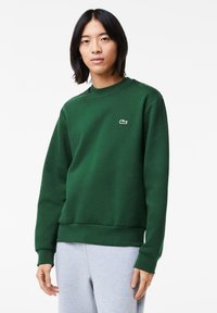 Grøn crewneck sweatshirts fremstillet af bomuldsblandingsstof, med et lille broderet logo på brystet og ribbede manchetter og kant.