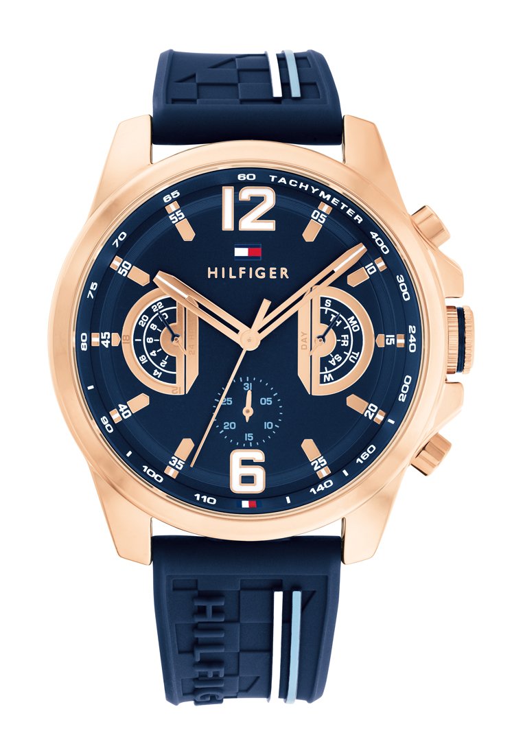 Niebieski zegarek chronograf z różowozłotą obudową, gumowym paskiem, dużymi oznaczeniami numerycznymi oraz subtarczkami do funkcji dnia i daty.