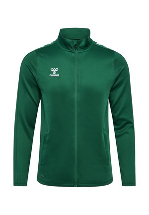 Grøn lynlåstrøje lavet af glat polyester, med høj krave, sidelommer og hvide skulderstriber. Hummel-logo på brystet.