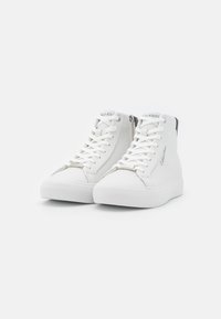 Bílé vysoké tenisky s hladkým koženým povrchem, vybavené tkaničkami, bočními zipy a diskrétním logem na jazyku a patě.