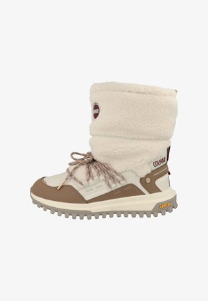 Botte d'hiver haute avec tige en shearling beige, détails en cuir marron, fermeture à lacets, et semelle Vibram robuste pour une bonne traction.