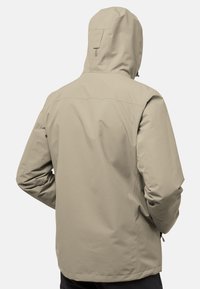Giacca impermeabile beige con cappuccio, texture liscia, polsini elasticizzati e orlo dritto. Presenta un giogo posteriore e tasche laterali.