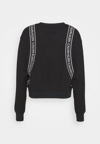 Sweat-shirt noir court à manches longues, avec des bretelles blanches marquées sur les épaules et un ourlet côtelé. Texture de tissu douce.