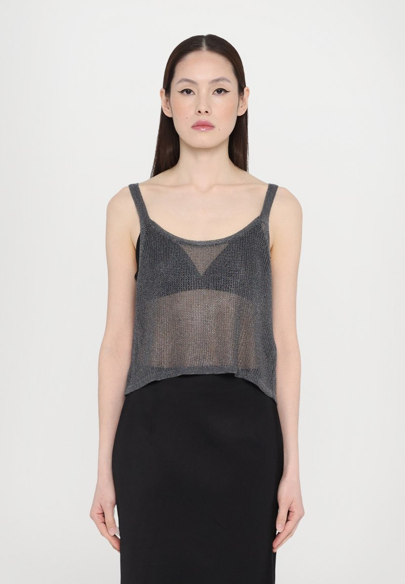 Grijze metalen gebreide crop top met dunne bandjes en een brede halslijn, gecombineerd met een zwarte rok met een transparante, gestructureerde afwerking.
