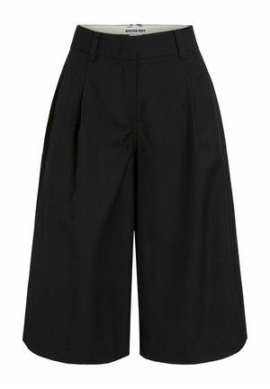 Shorts noirs larges jusqu'au genou avec passants de ceinture et plis sur le devant, étiquetés Rouge Edit à l'intérieur de la ceinture.