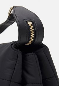 Czarna, pikowana torebka z podszewką o teksturowanym wykończeniu, z złotym detalem na zamku błyskawicznym i miękkim, pikowanym materiałem.