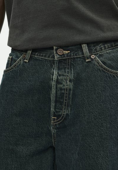 Donkergroene denimjeans met een zichtbare knoopsluiting en stiksels. Heeft zijzakken en een klassieke pasvorm. Gemaakt van katoen.