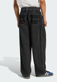 Black pinstriped pants with a relaxed fit, elastic waistband, and two back pockets. White stitching accents the design.