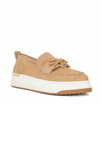 Tan suède instapper met een ronde neus, voorzien van een strikaccent en een witte platformzool. Stikdetails langs de randen.