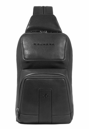 Mochila de cuero negro con un acabado texturizado, que presenta un bolsillo frontal con cremallera y un logo en relieve. Cremallera suave, forma aerodinámica, correas ajustables.