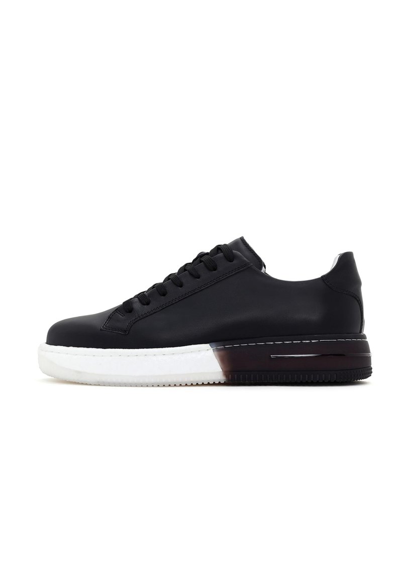 Sneaker noir en cuir avec un bout rond, un design sobre, une semelle en caoutchouc blanche et un accent de talon de couleur sombre contrastante. Doté d'un système de laçage.
