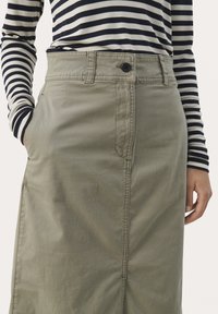 Jupe vert clair en coton, dotée d'une fermeture à boutons sur le devant, de poches latérales et d'une coupe droite avec des détails de couture visibles.