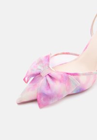 Γόβες με μυτερή μύτη σε παστέλ ροζ και μοβ χρώμα, με μεγάλο φόδρα ύφασμα στο μπροστινό μέρος και λουράκι στο πίσω μέρος.