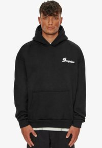 Hoodie noir en coton, avec une poche frontale, des poignets côtelés et un logo blanc sur la poitrine. Coupe classique avec une capuche à cordon de serrage.