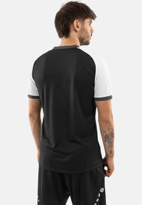 Zwart-witte sportshirt met korte mouwen en een ronde halslijn, met een contrasterend ontwerp op de schouders en een gladde stof.