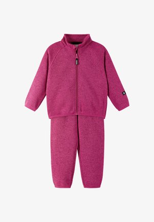 Bluza z zamkiem w kolorze fuksji z wysokim kołnierzem i długimi rękawami, zestawiona z dopasowanymi spodniami. Miękki, teksturowany materiał z niewielką ilością dodatków.