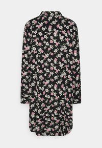 Camisa floral com fundo preto, apresentando flores rosa e brancas. Mangas longas, design com colarinho e bainha arredondada. Textura de tecido suave.