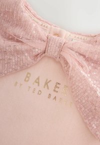 Šviesiai rožinė apranga su blizgučiais puoštu lankeliu prie kaklo, po lankeliu auksine spalva užrašyta "BAKER by TED BAKER". Minkšta tekstūra.