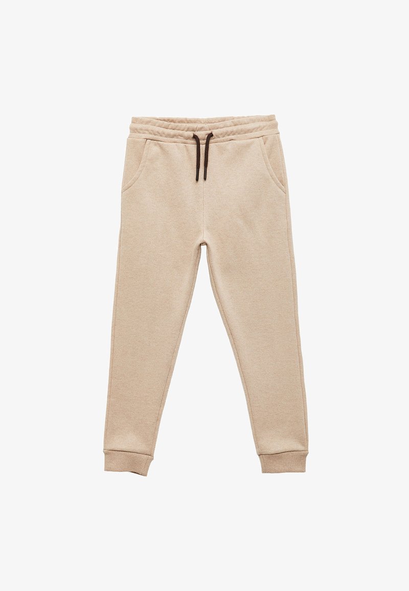 Beige sweatpants i mjukt tyg, med ett elastiskt midjeband och en brun dragsko samt sidofickor. Avsmalnande muddar vid anklarna.