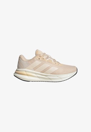 Zapatillas de running beige con una parte superior de malla ligera, tres rayas blancas, suela acolchada y suela de goma texturizada para mayor tracción.