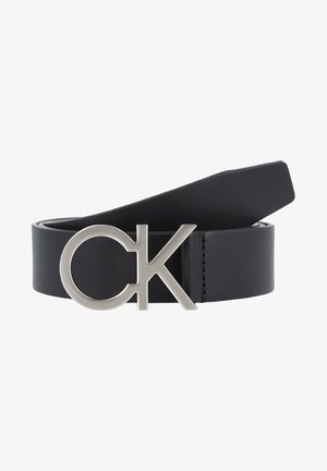 Cinto de couro preto com uma fivela de metal prateada com um design circular e as letras "CK" integradas na fivela.