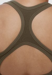 Oliivinvihreä urheilullinen tank top, jossa on urheilullinen selkädesign, valmistettu sileästä ja joustavasta kankaasta ja jossa on litteät saumat, luoden siistin ja minimalistisen ilmeen.