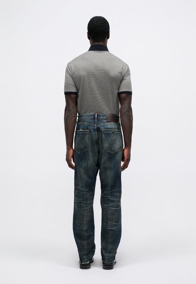 Grå og marinblå stripet polo-skjorte med korte ermer, kombinert med falmede blå denimjeans med baklommer og et lærmerke.