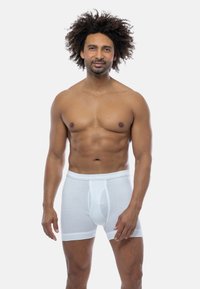 White cotton boxer briefs with a fitted design, elastic waistband, and a front pouch. Smooth texture and minimalistic style.