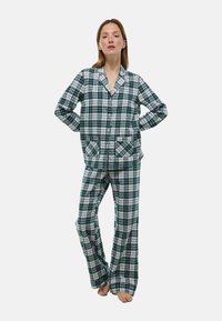 Ensemble de pyjama à carreaux verts et blancs comprenant un haut à boutons avec deux poches avant et un pantalon ample assorti, fabriqué dans un tissu doux et lisse.