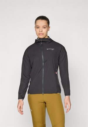 Black, lightweight, hooded jacket with a front zipper, mesh panels, and reflective accents. Worn over yellow, slim-fit pants.