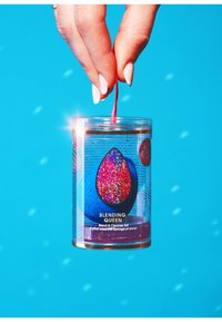 De Blending Queen set, verpakt in een heldere cilindervormige verpakking, bevat een blauwe spons met een glinsterende roze accenten, opgehangen aan een rode strik tegen een heldere achtergrond.