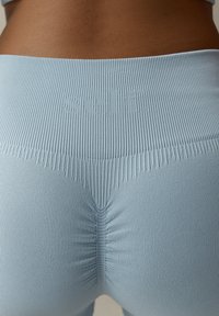 Lyseblå ribstrikkede leggings har et tekstureret stof, sømløst design med en samling detalje bagpå og et præget logo.