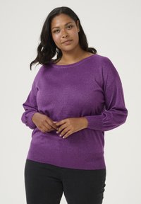 Purple glittery knit sweater with a wide neckline and long sleeves, featuring a ribbed hem and cuffs. Paired with black pants.