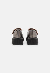 Gray leather shoes with a rounded shape, featuring a brown strap and decorative perforations. The black rubber sole has a ribbed texture.