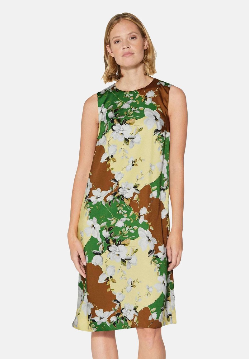 Blumenkleid mit ärmellosem Schnitt in Braun-, Grün- und Gelbtönen. Weicher Stoff mit weißen Blumenmotiven und glatter Textur.