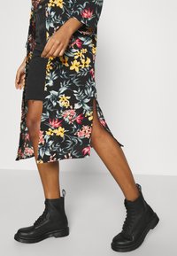 Czarny kimono w kwiatowy wzór z kolorowymi kwiatami, z bokami rozciętymi, w połączeniu z czarnymi botkami na sznurówki z grubą podeszwą.