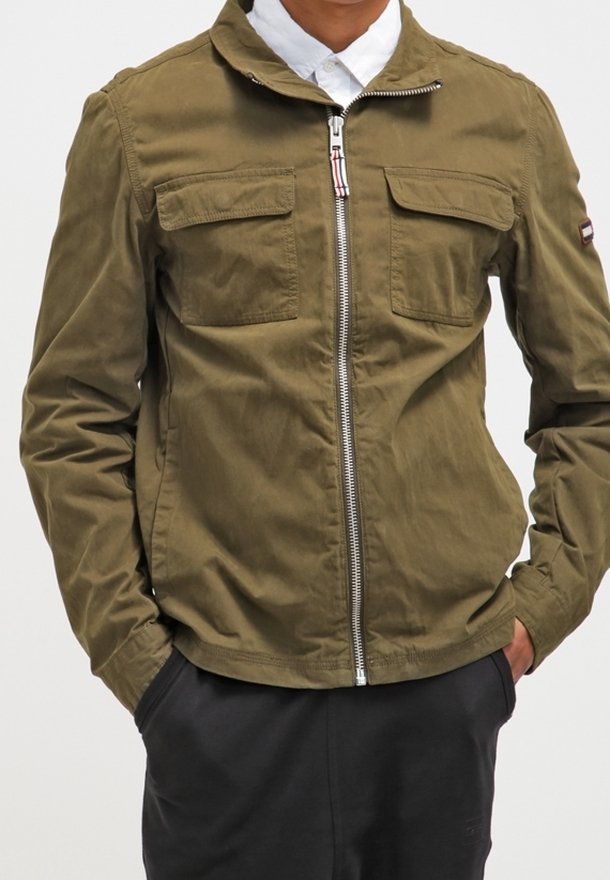 Olive green jacket with a zippered front, two chest pockets, and a stand-up collar. Fabric appears lightweight and smooth.