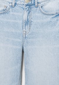 Blugi din denim albastru deschis, vedere apropiată, care arată buzunarele din față, fermoarul cu nasturi, buclele pentru curea și țesătura texturată.