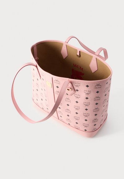 Ροζ τσάντα MCM χειρός με λουριά ώμου, με εξωτερικό μοτίβο με το λογότυπο και εσωτερικό σε μπεζ χρώμα με κόκκινα γράμματα και έμβλημα MCM.