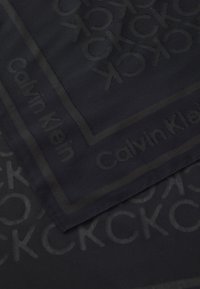 Sciarpa nera con motivo a rilievo del logo Calvin Klein, con bordo ed elementi ripetuti, realizzata in tessuto morbido.
