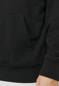 Zwarte sweatshirt met een voorzak, ribgebreide manchetten en onderrand. Gemaakt van zachte stof met een gladde textuur en zichtbare stikdetails.