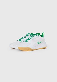 Bílé tenisky s zelenými akcenty, s texturovanou gumičkovou podrážkou, zaobleným designem a kontrastními tkaničkami. Výrazné logo Nike na boku.
